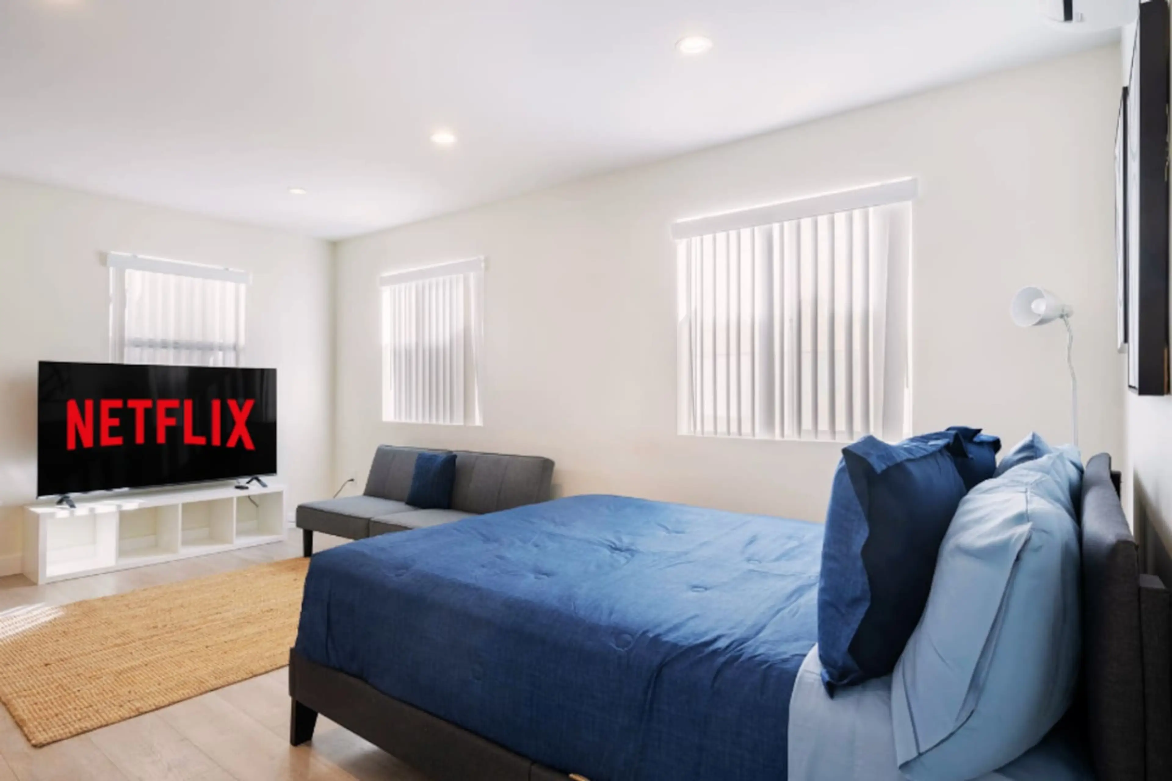 With TV, Sofa bed, Queen-sized bed dressed in rich blue bedding, floor lamp for added ambiance. The room's open layout flows seamlessly into the living area